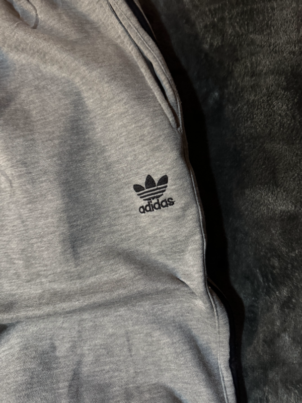 Pantalon Adidas gris lineas negras no original